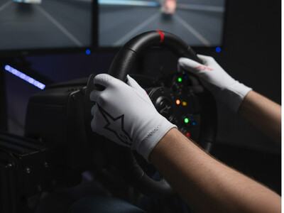 Person mit Alpinestars SimRacing Handschuhe am Lenkrad